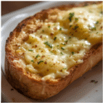 Sliced cheesy garlic bread with gooey cheese pull and crispy edges​