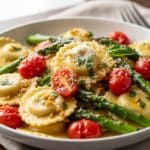 Ravioli with tomatoes and asparagus in olive oil with garlic and herbs, Parmesan garnish​