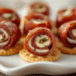 Close-up Salami Roll Ups with cream cheese, chives, and toothpicks on white platter.