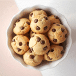 Low‑angle stack of tiny cookies with glossy mini chips.