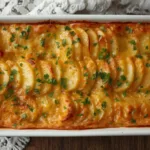 Sliced sweet potatoes arranged in an elegant pattern for Garlic Scalloped Sweet Potatoes, seasoned with fresh herbs and garlic.