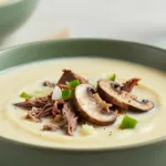Sliced steak in creamy cheese soup.