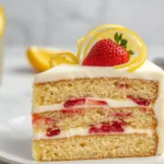 Slice of fresh Strawberry Lemonade Cake Layers showing the airy lemon sponge and the rich, red strawberry puree filling between layers.