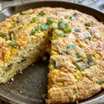 Vertical close-up shot of a wedge of Chiles Rellenos Cornbread with gooey cheese and green chiles.