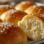 A basket of golden brown no knead buttermilk dinner rolls brushed with butter.