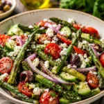 vibrant Charred Asparagus Greek Salad with feta and olives in a white bowl.